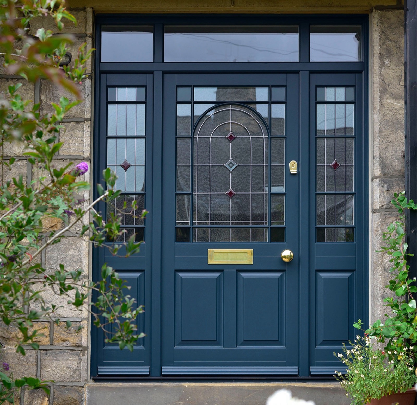 Navy painted timber front door with leaded stained-glass panels and brass furniture
