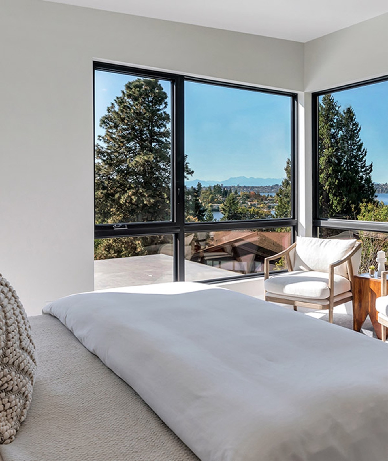 Bright bedroom with a timber corner window overlooking trees